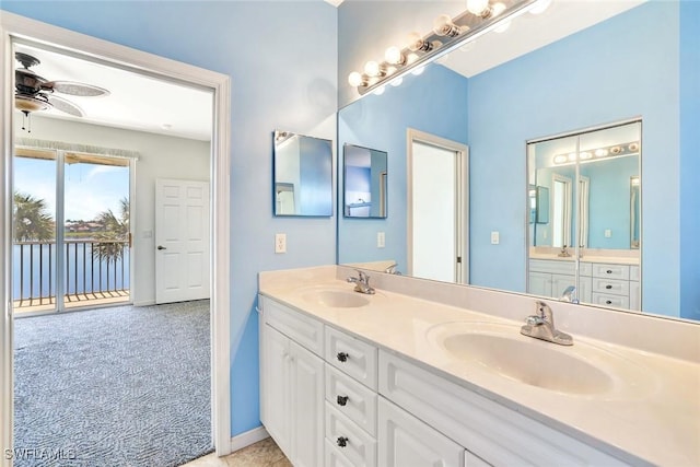 bathroom featuring a ceiling fan, a sink, baseboards, and double vanity