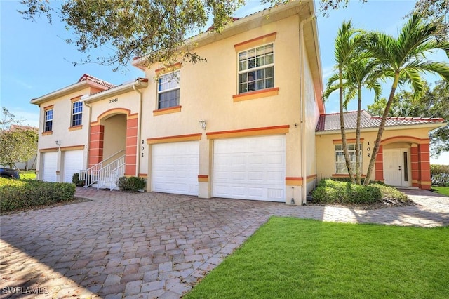 view of front facade featuring a tiled roof, decorative driveway, an attached garage, and stucco siding