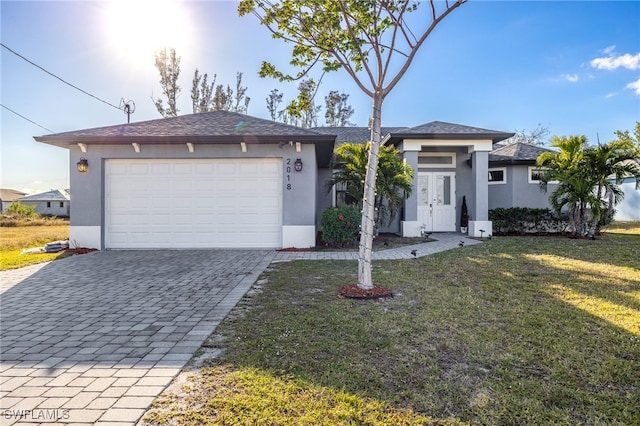 view of front of house with stucco siding, decorative driveway, a front lawn, and a garage