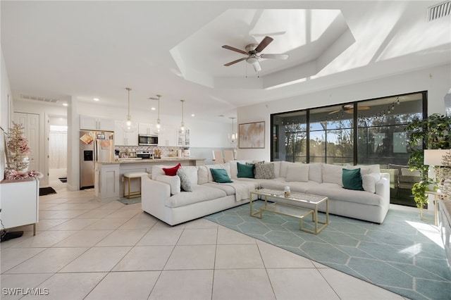 living room featuring a raised ceiling, visible vents, ceiling fan, and light tile patterned floors