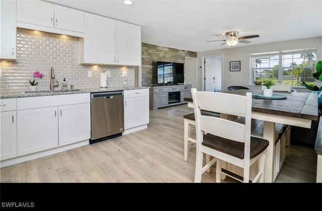 kitchen with a sink, backsplash, white cabinets, and stainless steel dishwasher