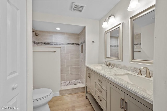 full bath featuring visible vents, a sink, toilet, and tiled shower