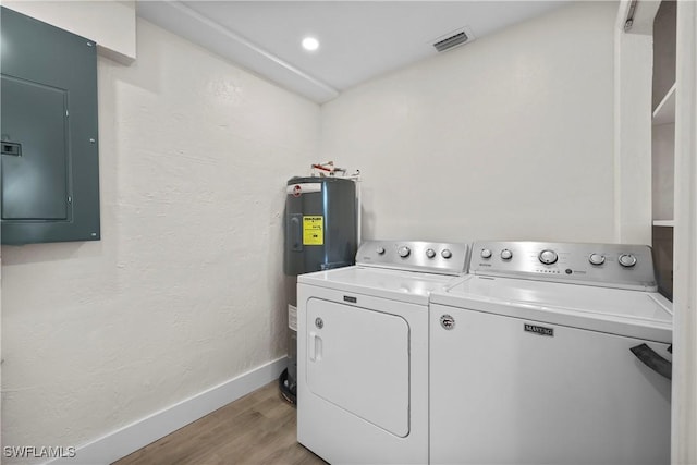 clothes washing area featuring electric panel, visible vents, independent washer and dryer, electric water heater, and light wood-style floors