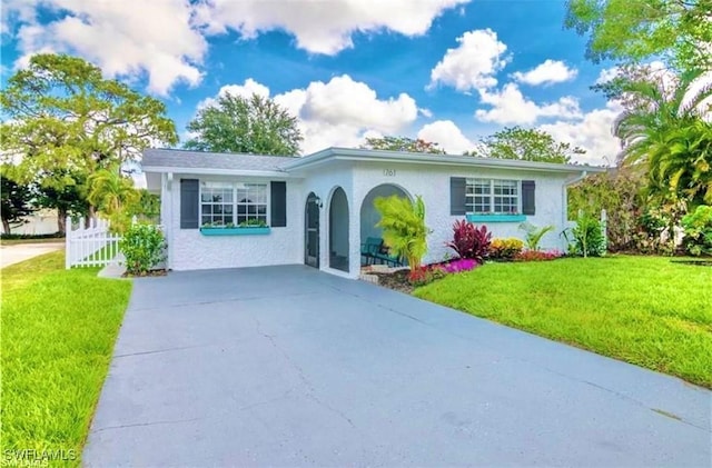 single story home featuring concrete driveway, a front yard, fence, and stucco siding