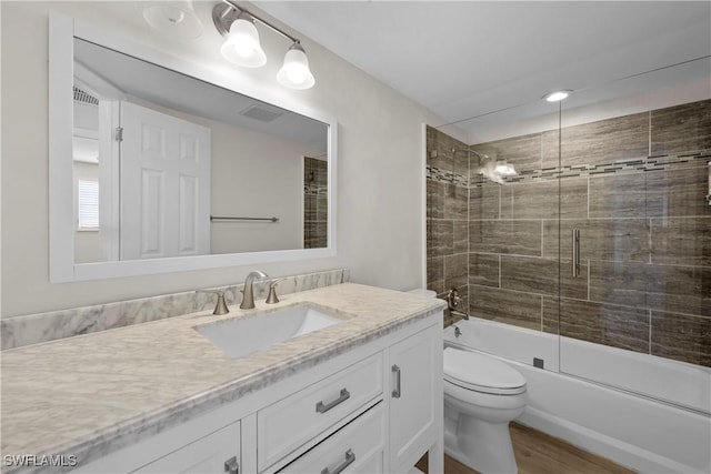 bathroom with enclosed tub / shower combo, toilet, wood finished floors, visible vents, and vanity