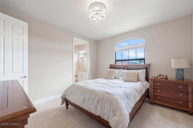 bedroom with light carpet, an inviting chandelier, ensuite bath, and baseboards