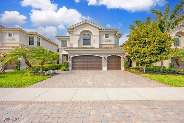 mediterranean / spanish-style home with a garage, decorative driveway, and stucco siding