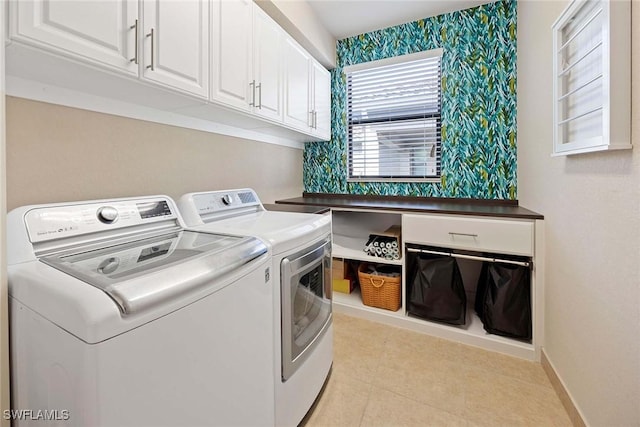 clothes washing area featuring washer and clothes dryer, cabinet space, light tile patterned flooring, baseboards, and wallpapered walls