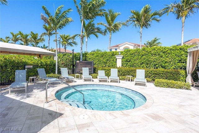 view of pool with a patio area, fence, and a hot tub