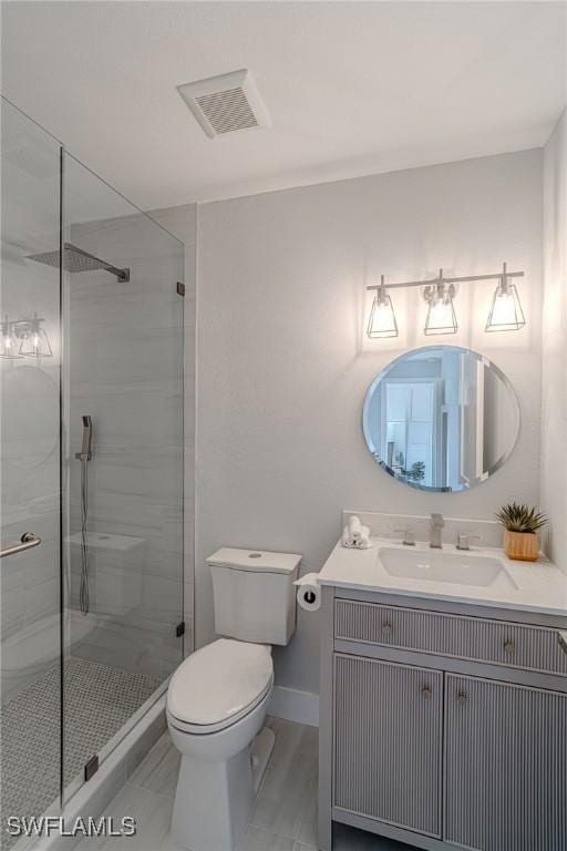 bathroom featuring toilet, vanity, visible vents, baseboards, and a shower stall