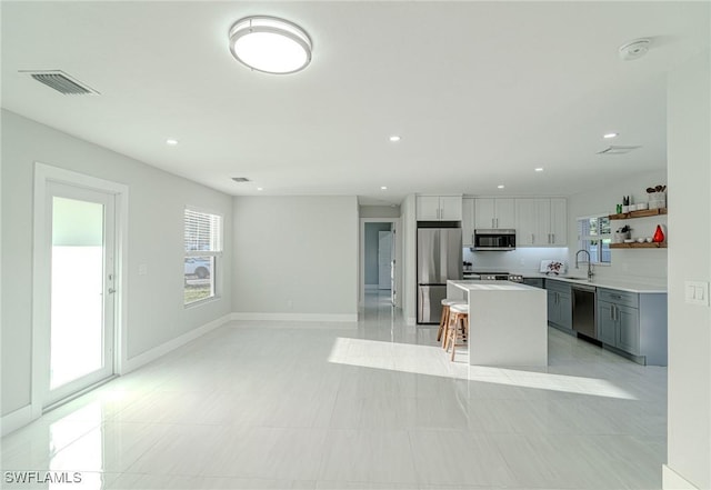 kitchen with open shelves, stainless steel appliances, light countertops, visible vents, and a sink