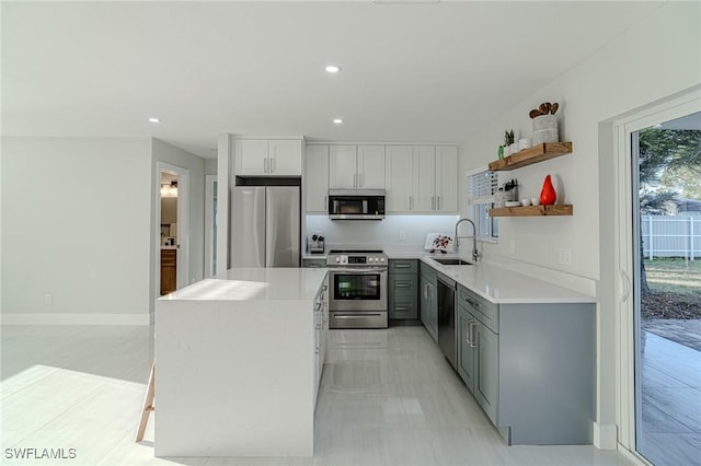 kitchen with a center island, gray cabinets, stainless steel appliances, open shelves, and a sink