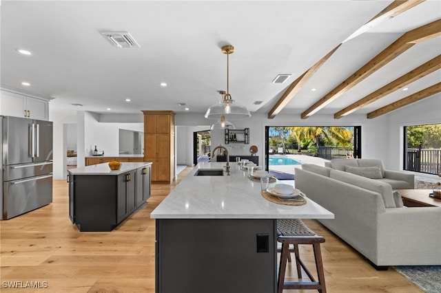 kitchen featuring a spacious island, visible vents, open floor plan, high end fridge, and a sink