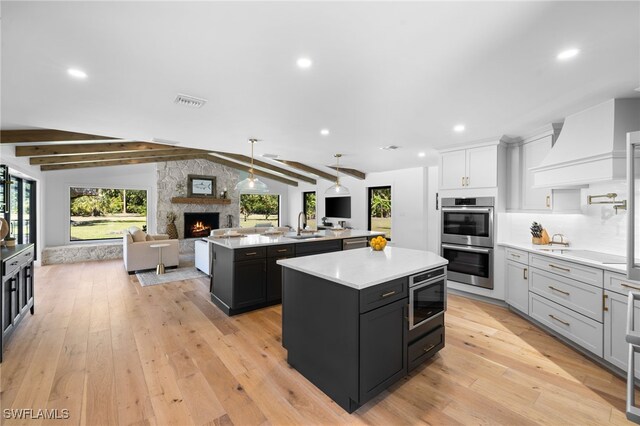 kitchen featuring a center island, premium range hood, lofted ceiling with beams, light countertops, and stainless steel double oven