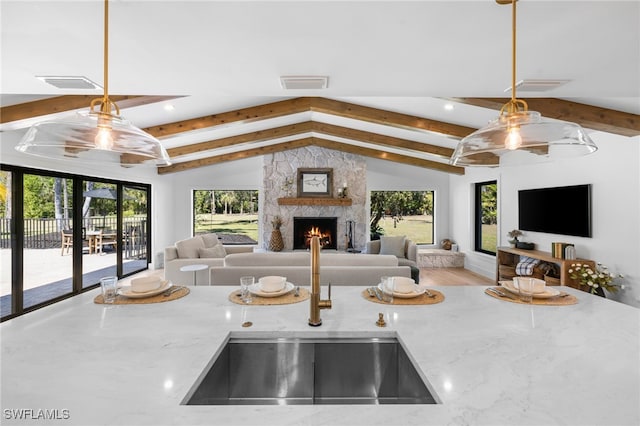 kitchen with a wealth of natural light, visible vents, lofted ceiling with beams, open floor plan, and a fireplace