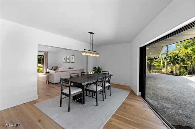 dining area featuring a notable chandelier, baseboards, and light wood-type flooring