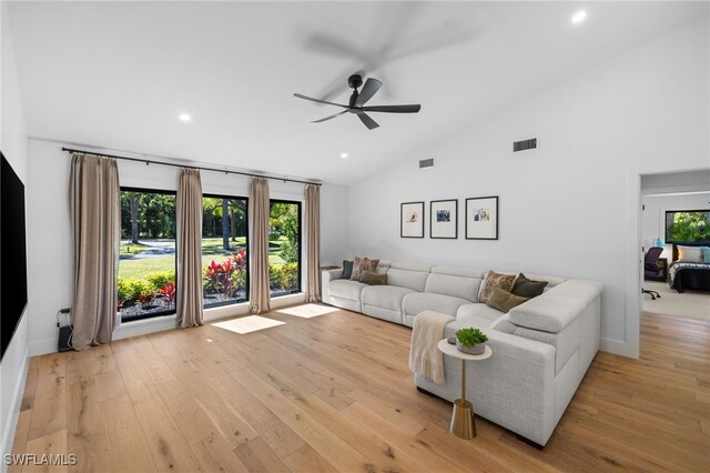 living area with visible vents, light wood-style floors, ceiling fan, and high vaulted ceiling