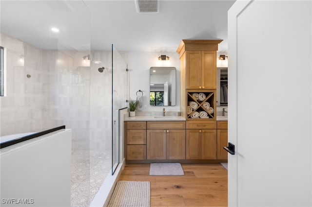 full bath featuring visible vents, vanity, walk in shower, and wood finished floors