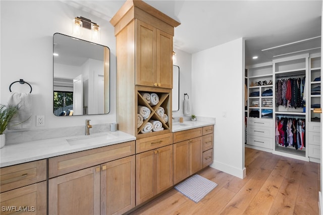 full bathroom featuring double vanity, a spacious closet, wood-type flooring, and a sink