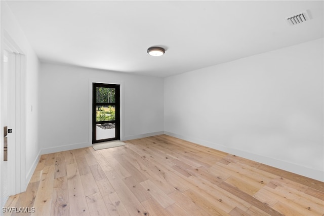 empty room featuring light wood-style floors, visible vents, and baseboards