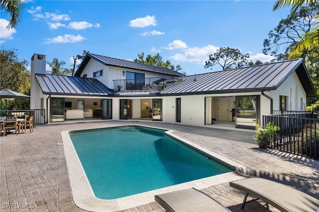 rear view of house featuring fence, a standing seam roof, stucco siding, a patio area, and metal roof