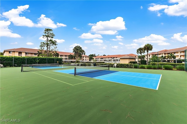 view of tennis court featuring a residential view and fence