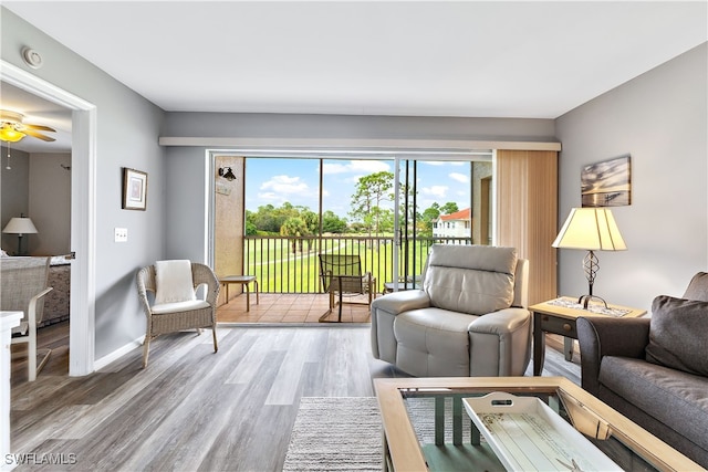 living area featuring wood finished floors, a ceiling fan, and baseboards