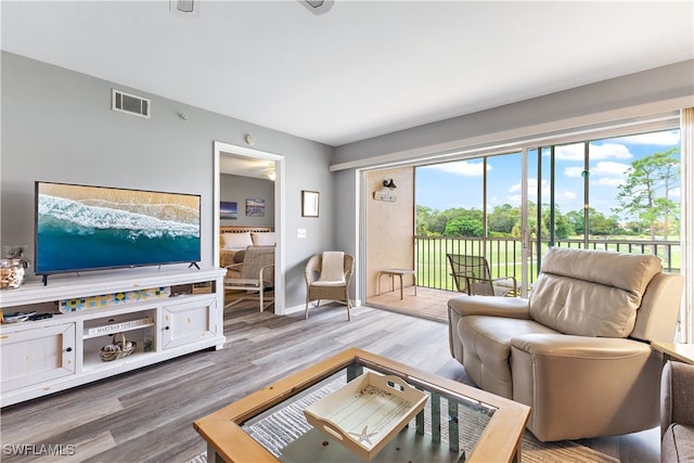 living room featuring wood finished floors, visible vents, and baseboards