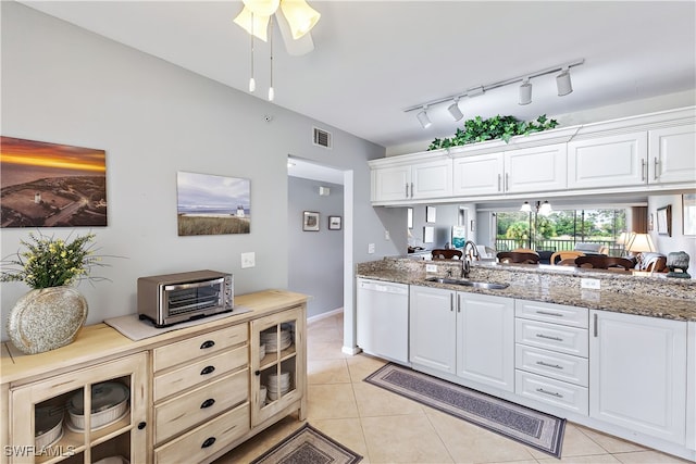 kitchen featuring stone counters, light tile patterned floors, visible vents, white dishwasher, and a sink