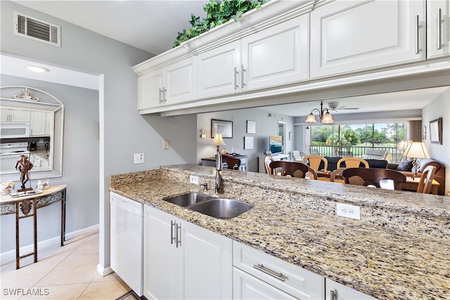 kitchen with white appliances, light tile patterned floors, visible vents, white cabinetry, and a sink