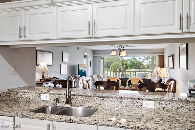 kitchen featuring white cabinets, a sink, and light stone countertops