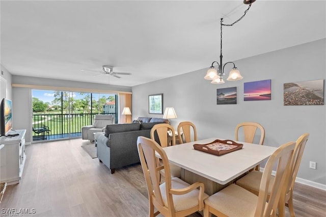 dining area with baseboards, wood finished floors, and ceiling fan with notable chandelier