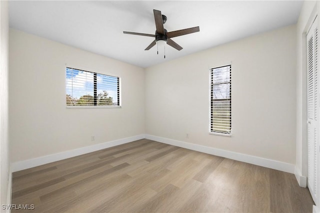 spare room with light wood-type flooring, ceiling fan, and baseboards