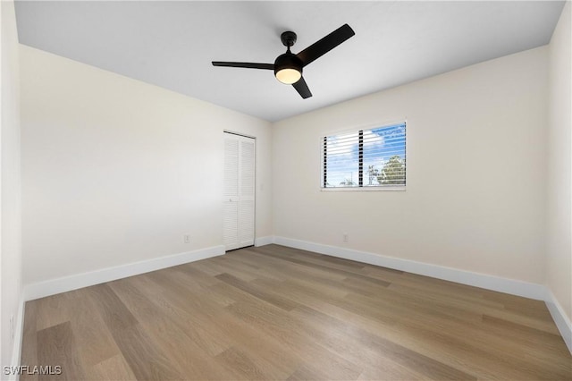 spare room featuring light wood finished floors, baseboards, and a ceiling fan