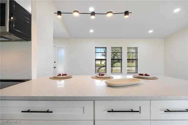 kitchen featuring light stone counters, white cabinets, and recessed lighting