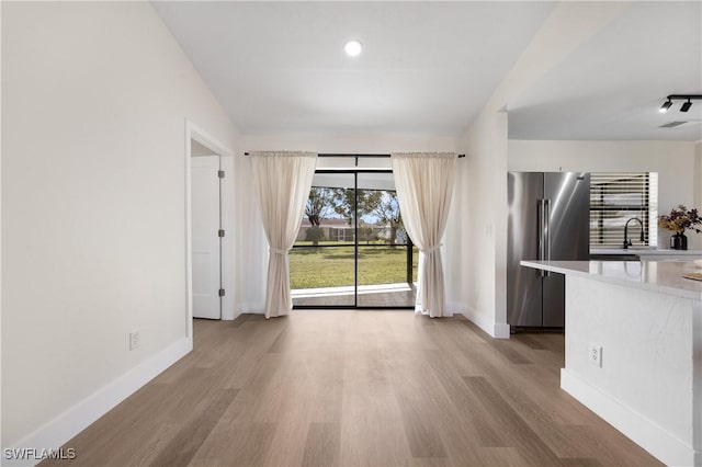 unfurnished living room with light wood-type flooring, visible vents, baseboards, and a sink