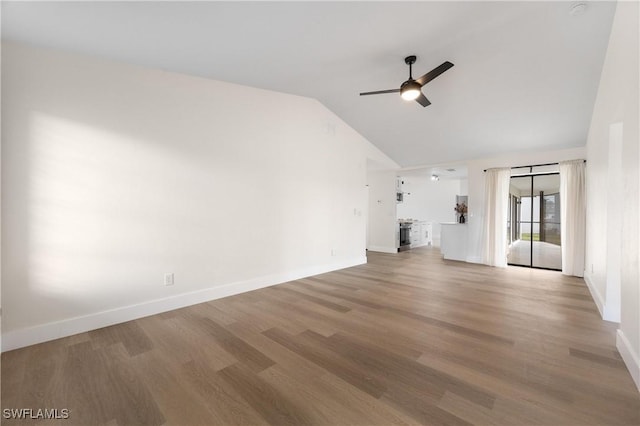 unfurnished living room with a ceiling fan, vaulted ceiling, baseboards, and wood finished floors