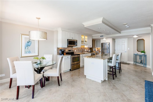 720 S Collier Blvd Unit 1007, Marco Island, FL 34145 - kitchen featuring appliances with stainless steel finishes, crown molding, a kitchen bar, tasteful backsplash, and glass insert cabinets