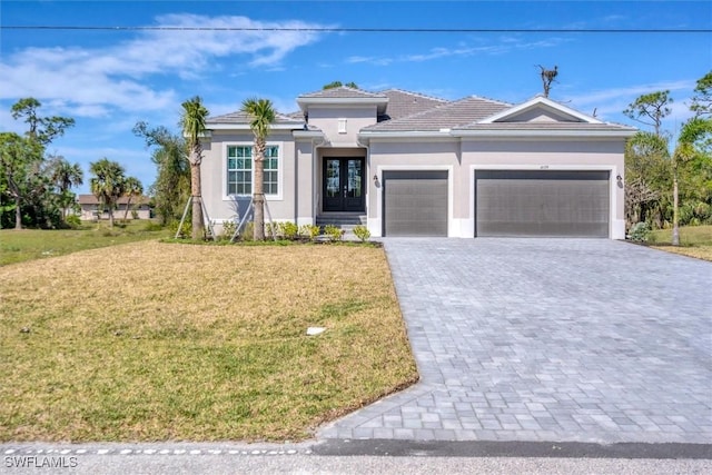 view of front of house with a garage, decorative driveway, a front lawn, and stucco siding