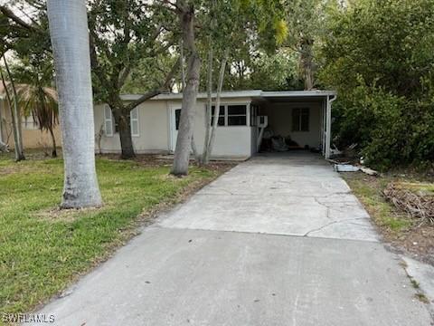 view of front of property with concrete driveway, an attached carport, and a front yard