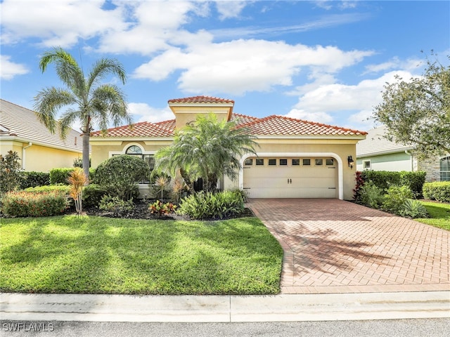 mediterranean / spanish home with a garage, a tiled roof, decorative driveway, a front lawn, and stucco siding