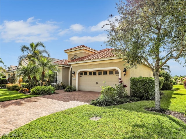 mediterranean / spanish house featuring a tiled roof, an attached garage, decorative driveway, a front lawn, and stucco siding