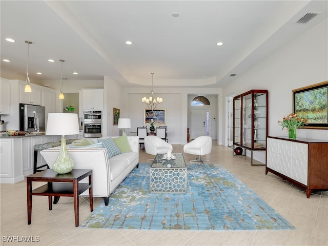 living area with light tile patterned floors, visible vents, a tray ceiling, a notable chandelier, and recessed lighting