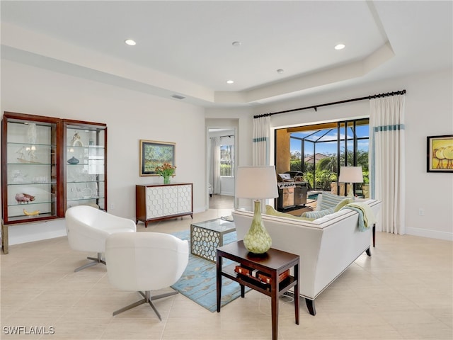 living area featuring recessed lighting, a raised ceiling, visible vents, and baseboards