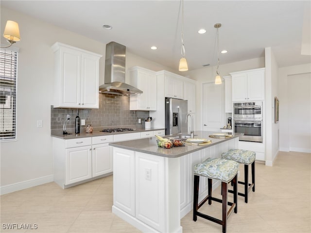 kitchen with white cabinets, wall chimney range hood, appliances with stainless steel finishes, and tasteful backsplash