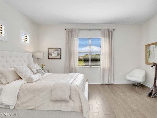 bedroom featuring multiple windows, baseboards, and wood finished floors