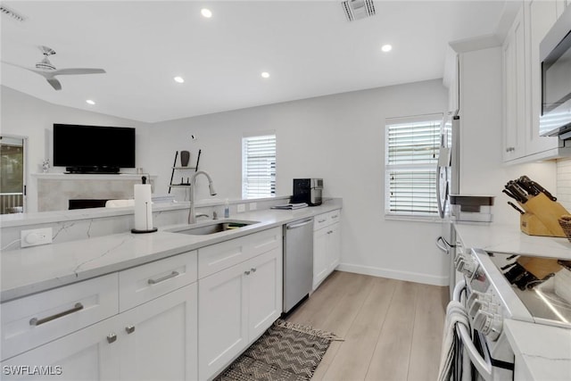 kitchen with visible vents, white cabinets, light wood-style flooring, appliances with stainless steel finishes, and a sink