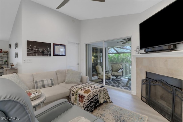 living room with a tiled fireplace, a sunroom, vaulted ceiling, ceiling fan, and wood finished floors