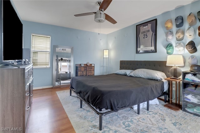 bedroom featuring ceiling fan, baseboards, and wood finished floors