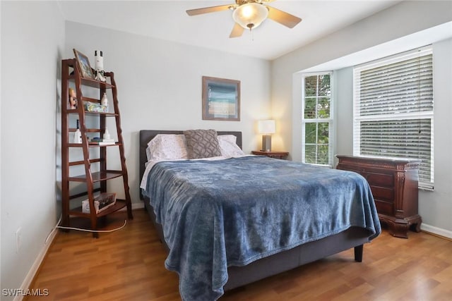 bedroom featuring ceiling fan, baseboards, and wood finished floors